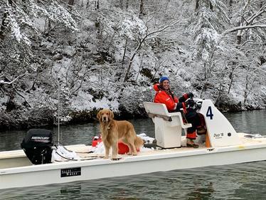 boat in a river with person and dog in winter