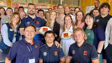 Darden students with boys holding rugby call