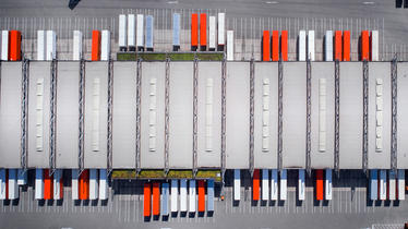 Overhead image of shipping warehouse with red and white trucks
