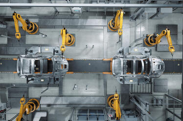 Automated car manufacturing assembly line with robotic arms building vehicle frames, illustrating modern supply chain and industrial automation