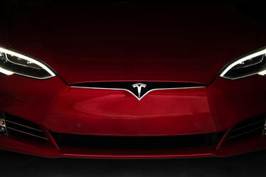 Front view of a red Tesla car with headlights on